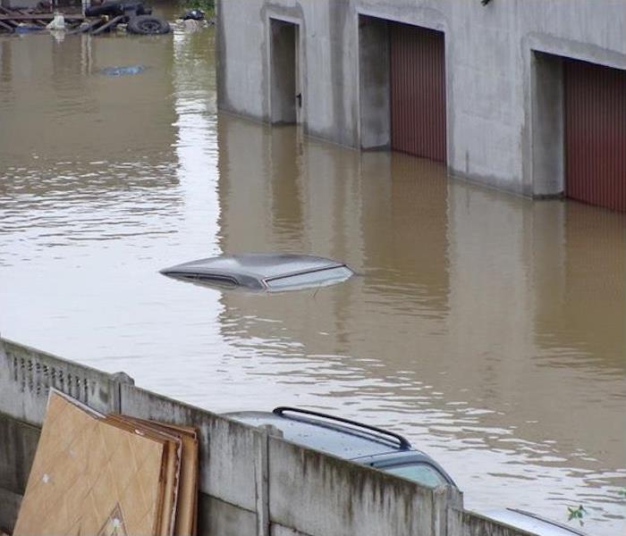 floodwaters covering car, bays of warehouse flooded