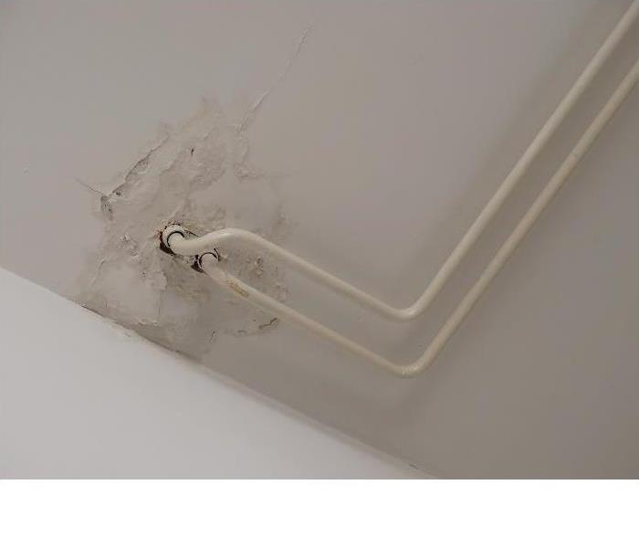 Water damage surrounding exposed pipes in ceiling